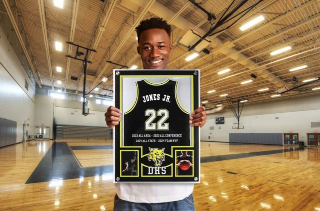 A picture of a senior holding his framed jersey
