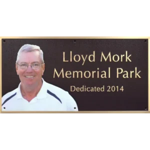 Bronze park memorial dedication plaque featuring a built-in full-color oval ceramic photo portrait.